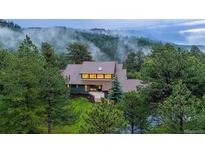 Secluded two-story home enveloped by lush trees and rolling hills with misty mountain views at 1952 Columbine Ct, Golden, CO 80401