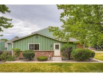 Charming exterior view of home with brick and green siding plus manicured lawn and landscaping at 400 S Balsam St, Lakewood, CO 80226