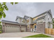 Charming two-story home with brick accents, three-car garage, manicured lawn, and inviting front porch at 6401 S Millbrook Way, Aurora, CO 80016