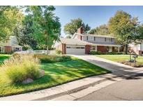 Charming two-story home featuring a well-manicured lawn and a long driveway leading to a two-car garage at 11754 W 28Th Ave, Lakewood, CO 80215