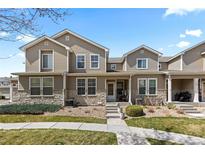 Charming townhome with a stone and siding exterior, complemented by a well-maintained lawn and inviting front porch at 9758 Laredo St # 18D, Commerce City, CO 80022