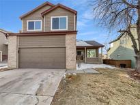Two-story home featuring a two-car garage, covered porch, and a mix of siding and brick accents at 9884 Florence Pl, Highlands Ranch, CO 80126