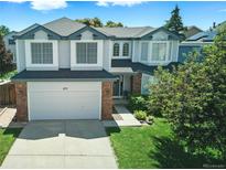 Charming two-story home boasts a manicured lawn, brick accents, and a two-car garage, nestled under a bright, partly cloudy sky at 275 S Pembrook St, Castle Rock, CO 80104