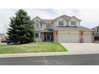 Charming two-story home with a well-manicured lawn and a large tree in front of the house at 11506 Greenbriar Ln, Parker, CO 80138