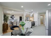 Open-concept kitchen with stainless steel appliances, white cabinets, and an island cooktop at 2202 S Grape St, Denver, CO 80222