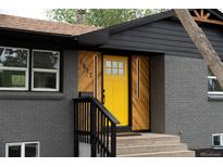 Charming home with a yellow front door, herringbone wood accents, and modern lighting at 1617 S Quitman St, Denver, CO 80219