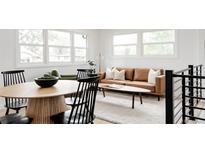 Bright living room with a brown leather couch, light rug, and large windows at 1617 S Quitman St, Denver, CO 80219