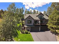 Stunning two-story home featuring lush landscaping, a deck, and an attached two-car garage at 31028 Big Bear Dr, Evergreen, CO 80439