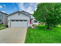 Charming two-story home featuring a well-manicured lawn, a two-car garage and a vibrant red front door at 215 Mcafee Cir, Erie, CO 80516
