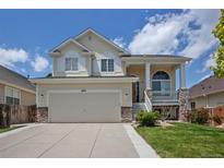 Inviting two-story home with a two-car garage, charming porch, stone accents, and a well-maintained lawn at 245 Homestead Way, Brighton, CO 80601
