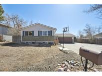 Charming home featuring a well-manicured lawn and a basketball hoop over the garage at 16622 E Asbury Ave, Aurora, CO 80013