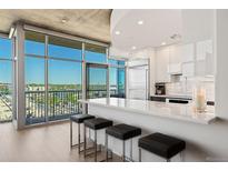 Bright kitchen with floor-to-ceiling windows, sleek cabinets, island seating, and stainless steel appliances at 1700 Bassett St # 1014, Denver, CO 80202