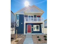 Charming two-story home featuring a balcony, a red front door, and low-maintenance landscaping at 45016 Sunflower Ln, Bennett, CO 80102