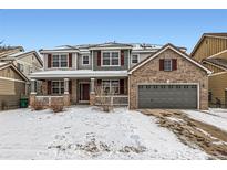 Two-story brick home with gray garage door and snowy front yard at 12232 S Great Plain Way, Parker, CO 80134