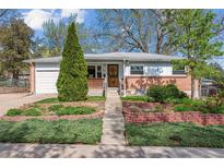 Charming single-story home featuring a brick facade, well-kept lawn and mature trees at 6882 Moore St, Arvada, CO 80004