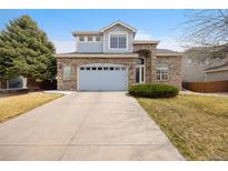 Charming two-story home with brick and light blue accents, a well-manicured lawn, and an attached two-car garage at 13078 Monaco Way, Thornton, CO 80602