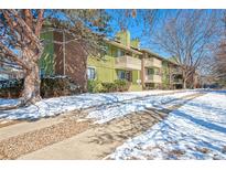 Exterior view of a green condominium building with brick accents and balconies in a winter setting at 2800 Kalmia Ave # B209, Boulder, CO 80301