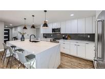 Renovated kitchen boasting white cabinets, hexagon backsplash, and a large island at 7076 S Newland St, Littleton, CO 80128