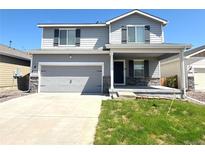 Charming two-story home with a gray exterior, landscaped yard, covered porch, and a two car garage at 47373 Lily Ave, Bennett, CO 80102