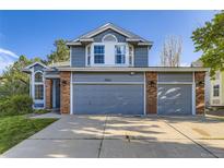 Charming two-story home featuring a three-car garage, blue siding, brick accents, and manicured lawn at 5645 S Himalaya Way, Centennial, CO 80015
