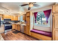 Bright kitchen featuring wood cabinets, stainless steel appliances, granite countertops, and a window bench at 6233 W 75Th Ave, Arvada, CO 80003