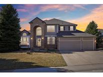 Beautiful two-story home featuring a three car garage and lush green lawn at sunset at 532 Adam Pl, Castle Pines, CO 80108