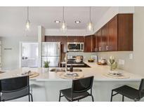 Modern kitchen with stainless steel appliances, white countertops, and breakfast bar seating at 10550 W Jewell Ave # 301, Lakewood, CO 80232