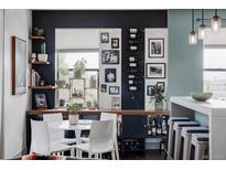 Stylish dining area featuring a white table, white chairs, shelves, and built-in bar storage for a modern and elegant aesthetic at 3420 W 32Nd Ave # 203, Denver, CO 80211