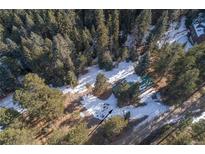 Aerial view of property showing home nestled in snowy woods at 5925 Herzman Dr, Evergreen, CO 80439