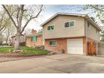 Split-level home featuring a brick and siding exterior, showcasing an attached garage and inviting curb appeal at 10878 Patterson Ct, Northglenn, CO 80234