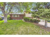 Charming two-story brick home with a well-maintained lawn and mature trees at 1462 S Dudley St, Lakewood, CO 80232