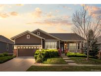 Charming ranch-style home with a well-manicured lawn, mature landscaping, and covered front porch at sunset at 21780 E Heritage Pkwy, Aurora, CO 80016