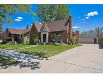 Charming brick home featuring a well-maintained lawn, a turret and a long driveway leading to a detached garage at 4434 Grove St, Denver, CO 80211