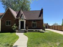 Charming brick home featuring a turret-style entrance and beautifully manicured front lawn and walkway at 4434 Grove St, Denver, CO 80211