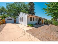 Charming light blue single-story home with a detached garage and a long driveway on a sunny day at 2205 S King St, Denver, CO 80219