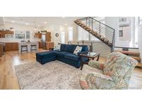 Open living area featuring a comfortable blue sectional, hardwood floors, and a modern staircase at 5610 S Sycamore St, Littleton, CO 80120
