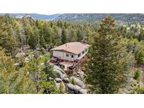 Scenic mountain home featuring a private deck and surrounded by lush forest and natural rock formations at 8701 Majestic View Dr, Conifer, CO 80433