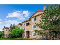 Condo complex featuring manicured landscaping, stone accents, and a private balcony on a sunny day at 8520 S Holland Ln # 102, Littleton, CO 80128