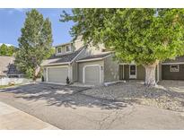 Traditional townhome showcasing a two-car garage, tidy landscaping, and charming curb appeal at 10685 W Apishapa Pass, Littleton, CO 80127