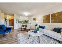 Open-concept living room with cozy seating, decorative artwork, and seamless transition to the dining area at 7420 E Quincy Ave # 304, Denver, CO 80237