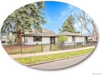 Charming single-story home with a black iron fence, lush lawn, mature trees, and a well-maintained garden at 755 S Milwaukee St, Denver, CO 80209