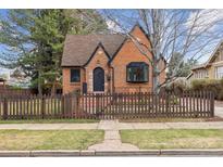 Charming brick home featuring a well-manicured lawn and a quaint picket fence at 2910 Clermont St, Denver, CO 80207
