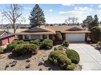 Charming brick ranch-style home featuring a well-maintained yard with mature landscaping and an attached two-car garage at 7240 Teller St, Arvada, CO 80003