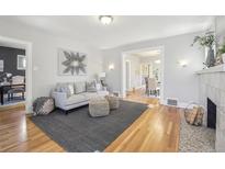 Bright living room boasts hardwood floors, gray couch, and decor, adjacent dining area and fireplace at 1462 Eudora St, Denver, CO 80220