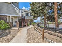 Charming condo with beautiful landscaping, exterior brick accents, mature trees, and painted wooden staircases at 909 S Dawson Way # 2, Aurora, CO 80012