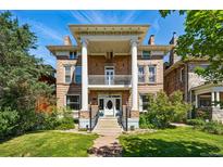 Stunning brick home featuring prominent columns, a second-story balcony, and lush landscaping at 1438 N Franklin St # 100, Denver, CO 80218