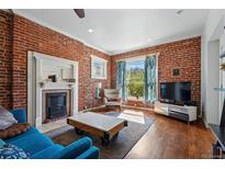 Bright living room featuring exposed brick, hardwood floors, and a decorative fireplace for a cozy atmosphere at 1438 N Franklin St # 100, Denver, CO 80218