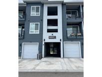Modern condo building with gray siding, white trim, private balconies, and attached garages for convenient parking at 16841 Askins Loop # 208, Parker, CO 80134