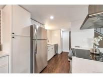 Bright kitchen featuring stainless steel appliances, white cabinets, and hardwood floors at 3355 S Flower St # 95, Lakewood, CO 80227