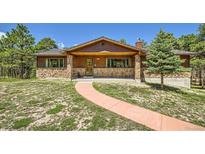 Charming home featuring a stone-clad facade and a welcoming front porch at 18150 Martingale Rd, Monument, CO 80132